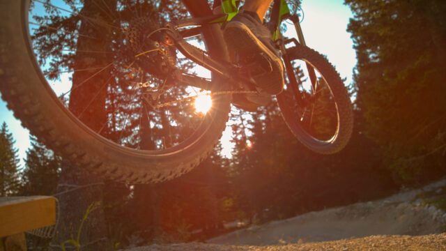 CLOSE UP Unrecognizable man on electric bike jumps as he rides a