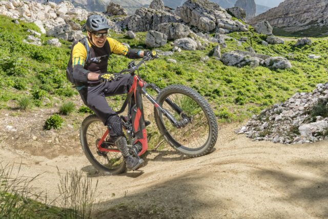 E bike rider in middle age enjoys the power of the e bike on a steep uphill trail.